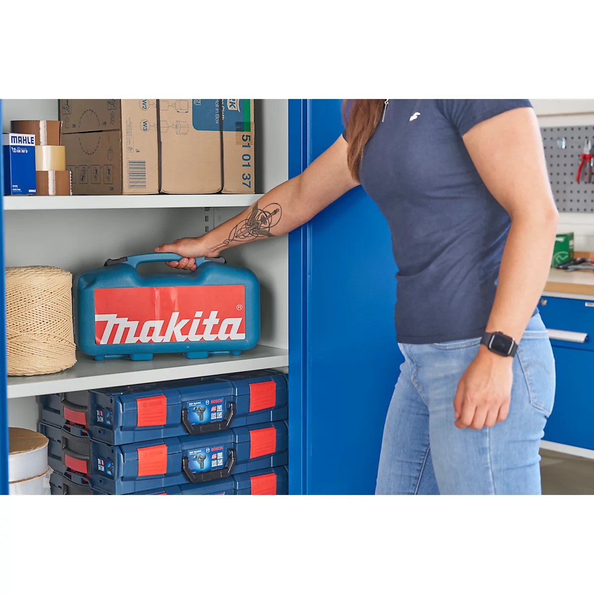 Persoon reikt naar een Makita gereedschapskist in een blauwe kast.