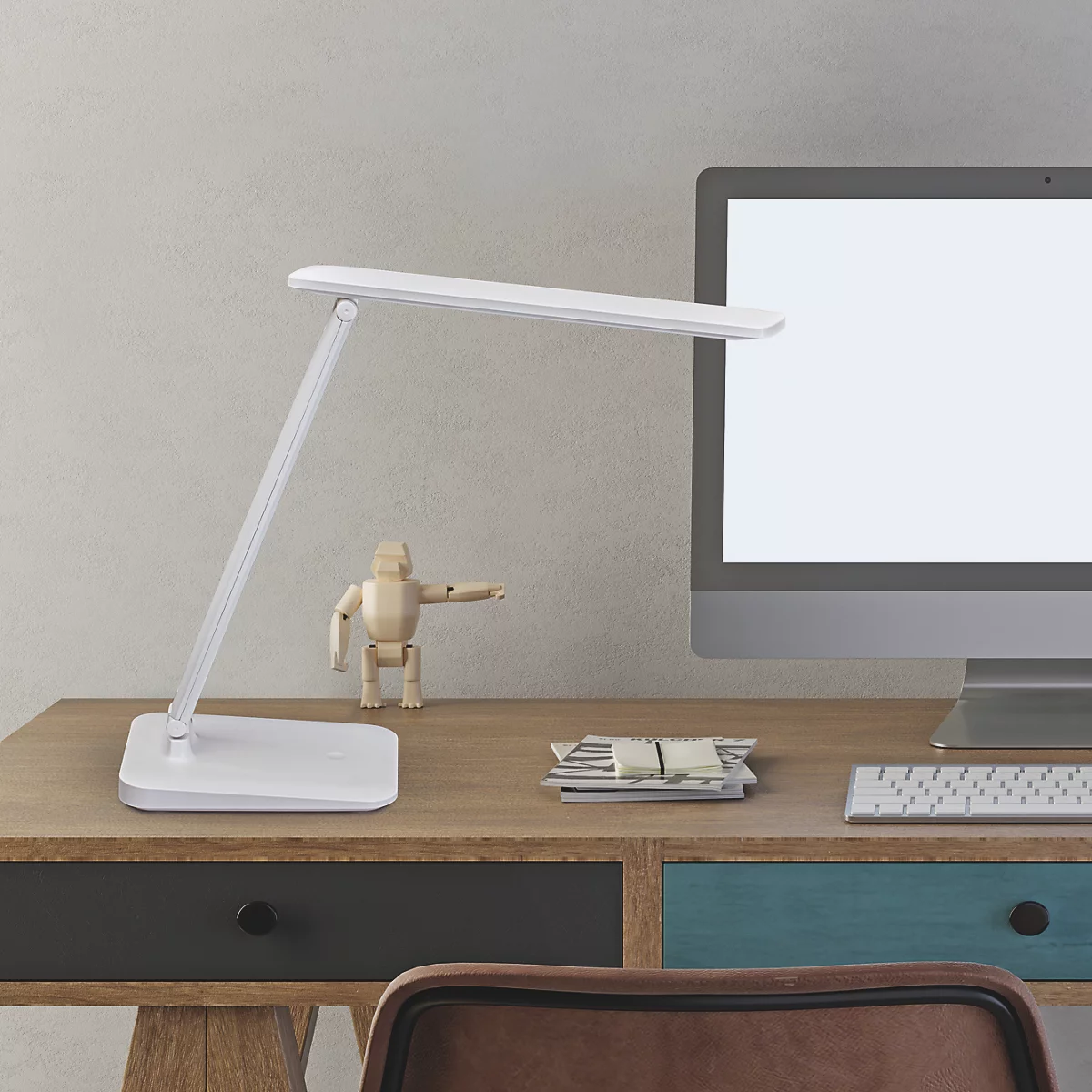 Lampe de bureau blanche sur un bureau avec ordinateur, poupée en bois et documents. Lieu de travail moderne.