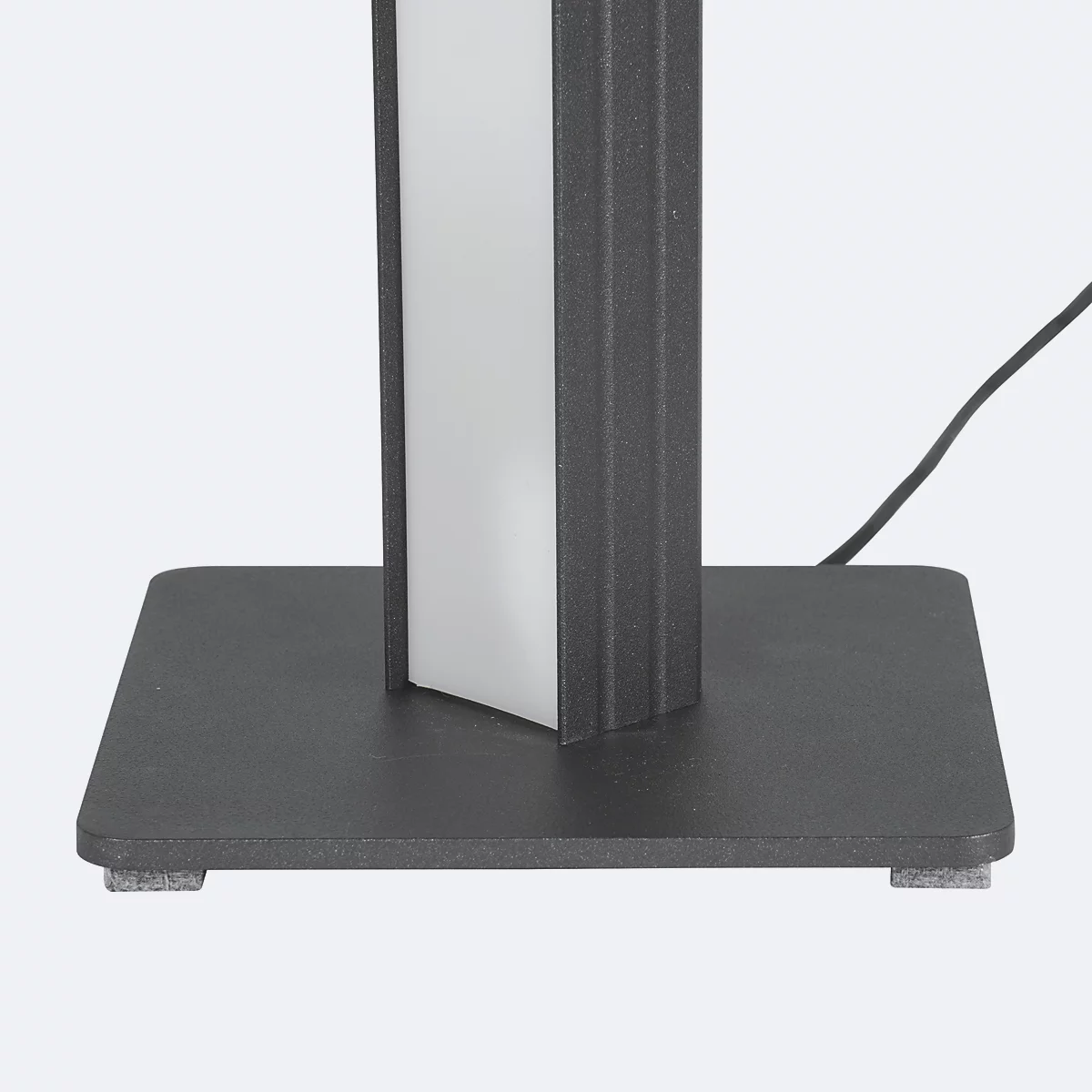 Detailaufnahme einer schwarzen Standleuchte. Der Schaft zeigt einen weißen Leuchtstreifen und steht auf einem schwarzen, quadratischen Fuß. Ein Kabel führt nach hinten.