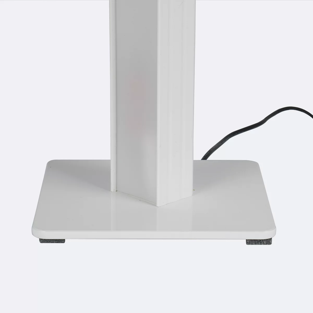 Nahaufnahme eines weißen Objekts mit quadratischer Basis und Säule, Stromkabel im Hintergrund.