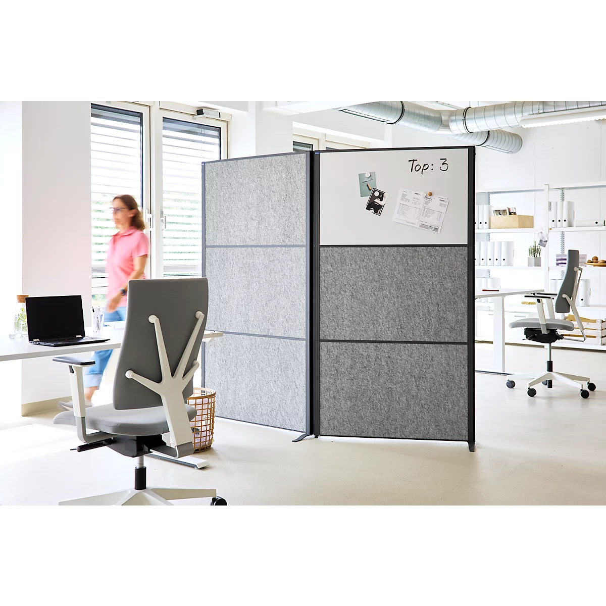 Modulare Stellwand mit grauen Filzpaneelen und Whiteboard in einem hellen Büro.