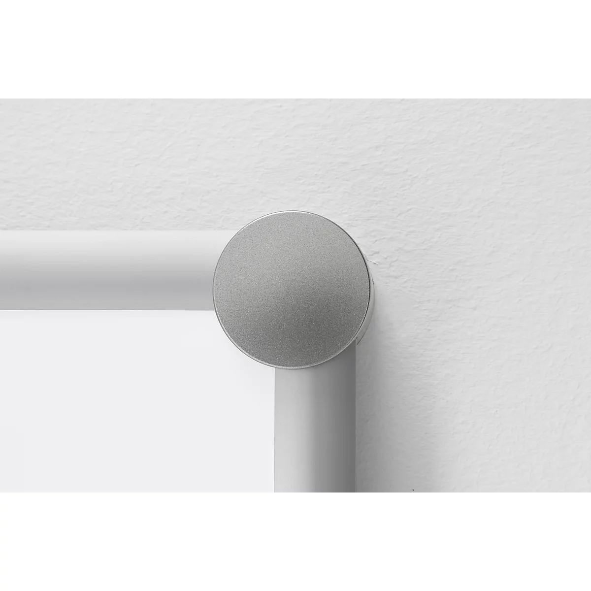 Grey round button on a white bar attached to a white wall.