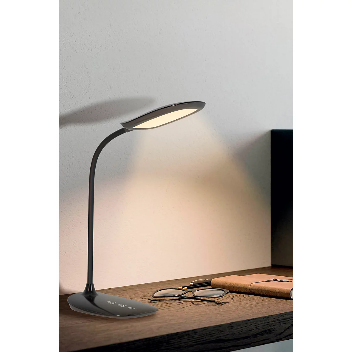 Schwarze LED-Schreibtischlampe, schwenkbar. Sie steht auf einem Schreibtisch, daneben liegen Brille und Notizbuch.