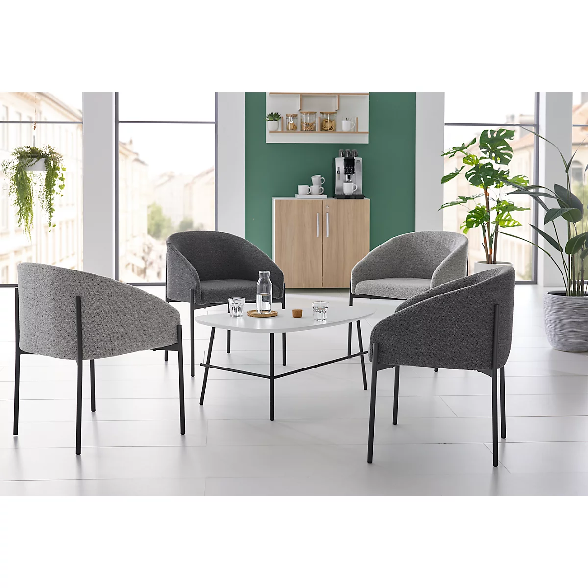 Vier stoelen rond een tafel in een woonkamer. Op de tafel een waterfles, glazen.