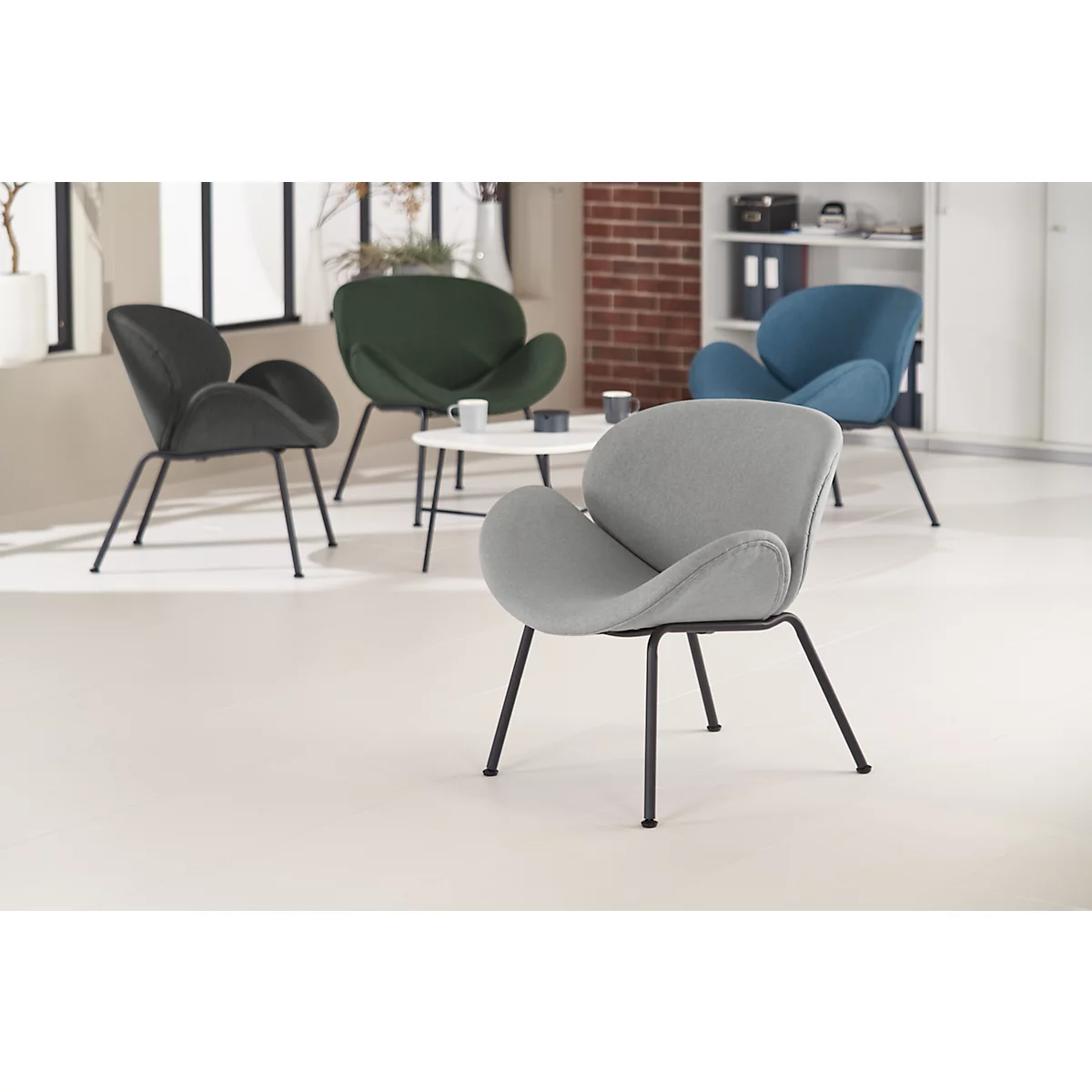 Vier Designerstühle, die im Kreis um einen kleinen Tisch angeordnet sind. Die Stühle sind in Grau, Schwarz, Grün und Blau gehalten.