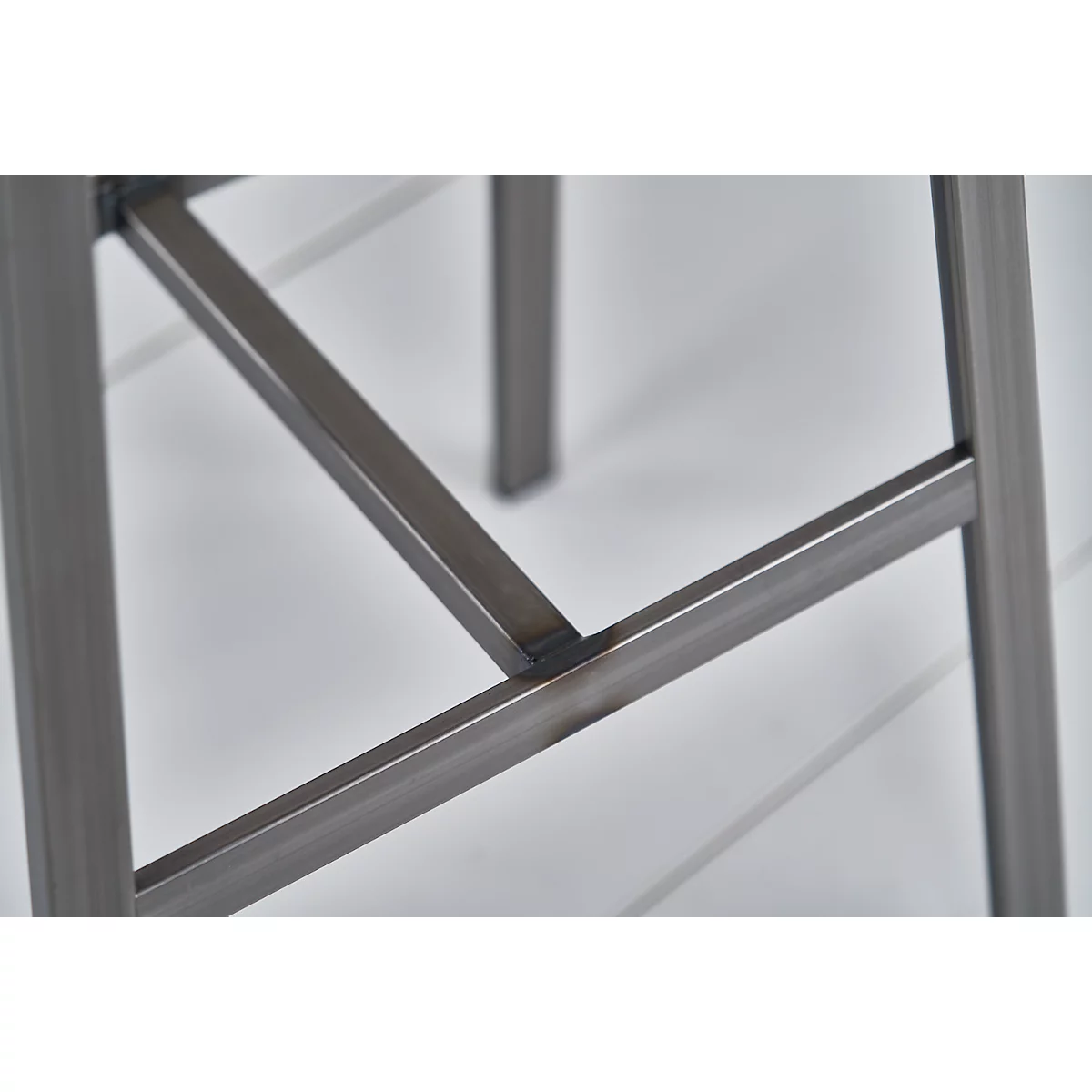 Close-up of a metal stool: Angles of metal struts connected with welds.