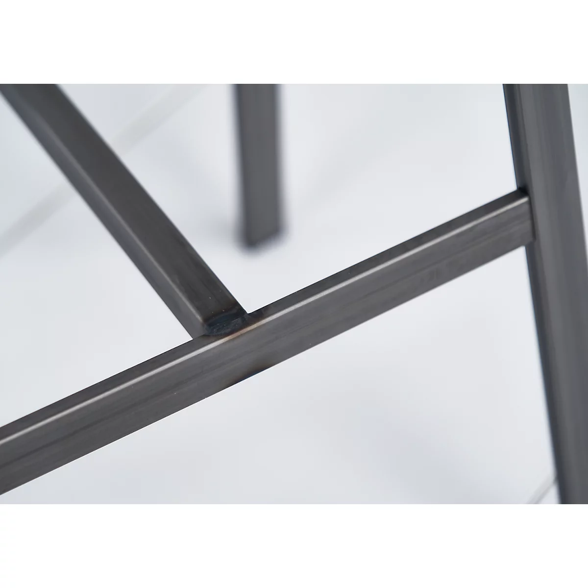 Close-up of the corner joint of a metal frame. Welded, dark grey on a light background.