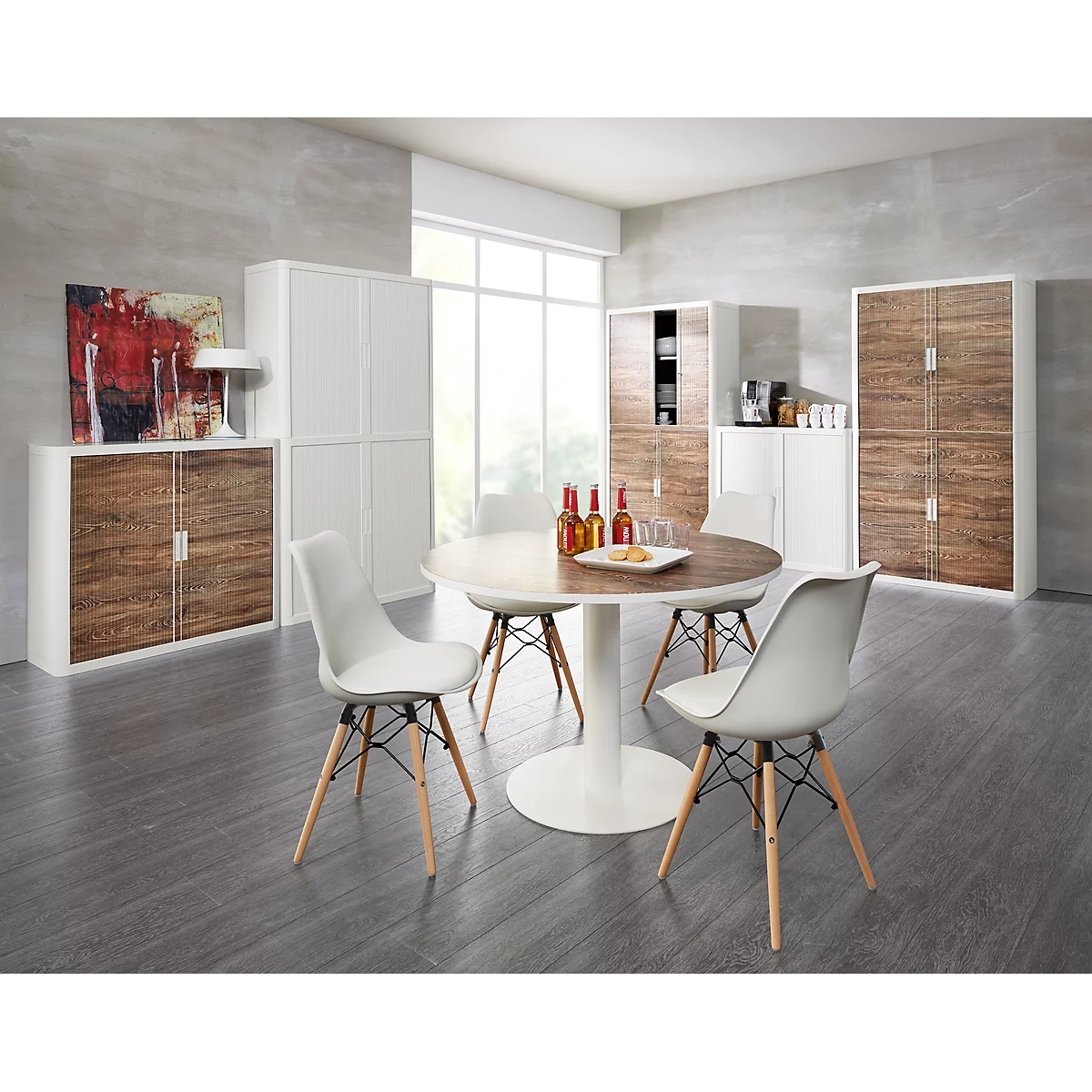 Dining room with wooden table, white chairs, and white cabinets. A painting and a lamp are also in the room.