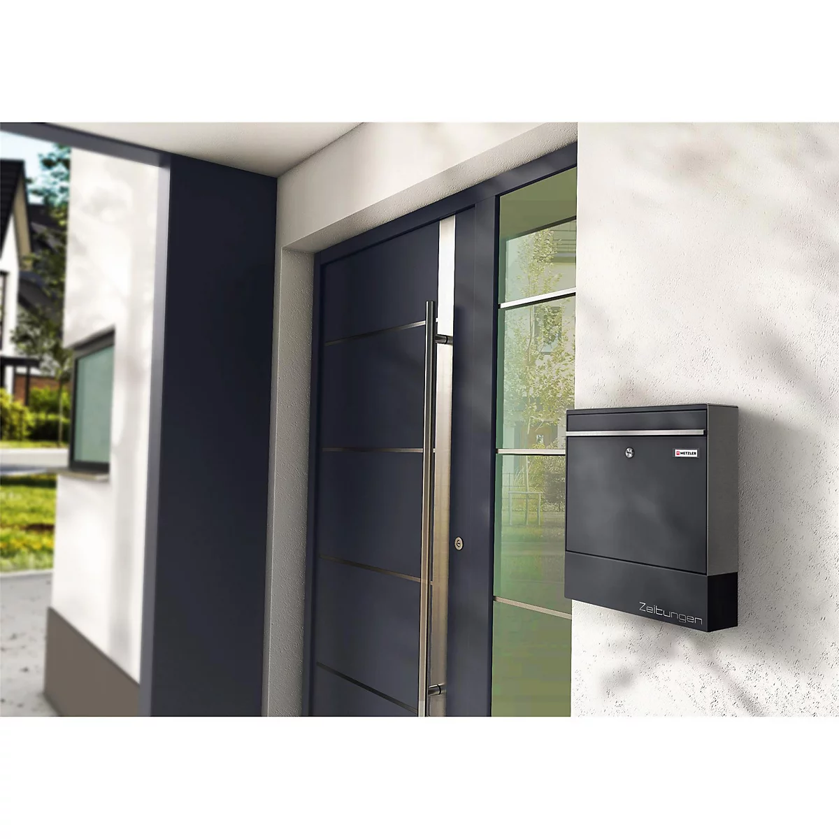 Boîte aux lettres noire fixée au mur à côté d'une porte d'entrée sombre. La photo a été prise à l'extérieur.