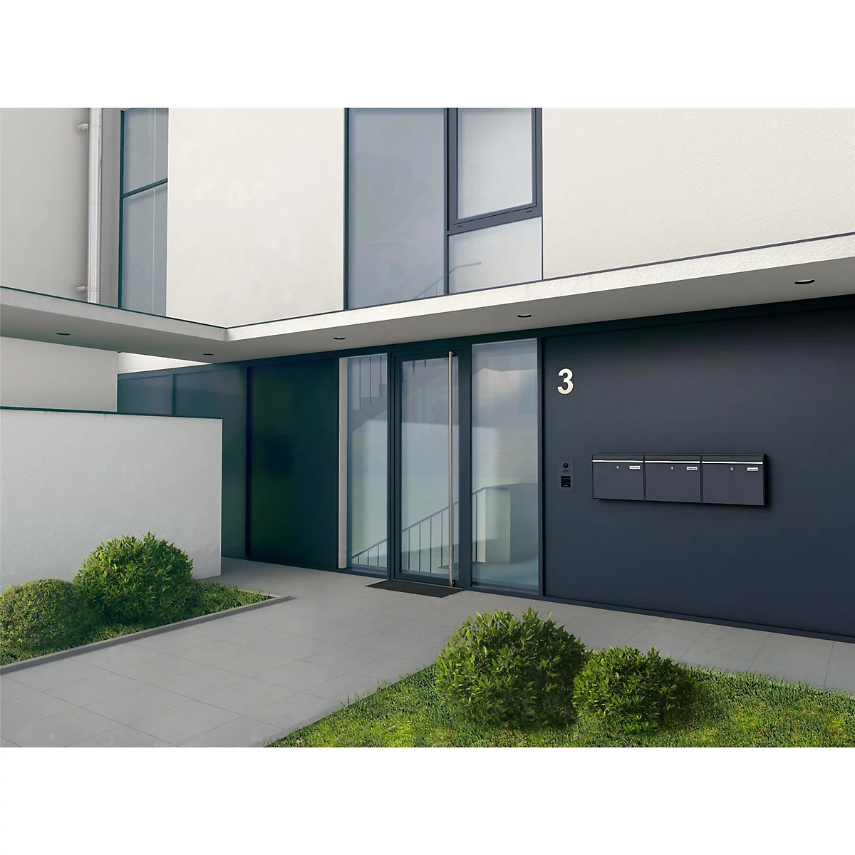 Moderne Hausfassade mit Haustür, Briefkästen und der Hausnummer 3. Vor dem Eingang grünes Gras und Büsche.