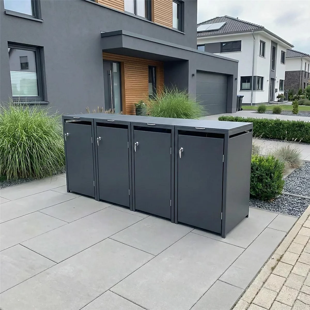Graue Mülltonnenbox vor einem modernen Haus. Nebenweg mit Hausnummer.