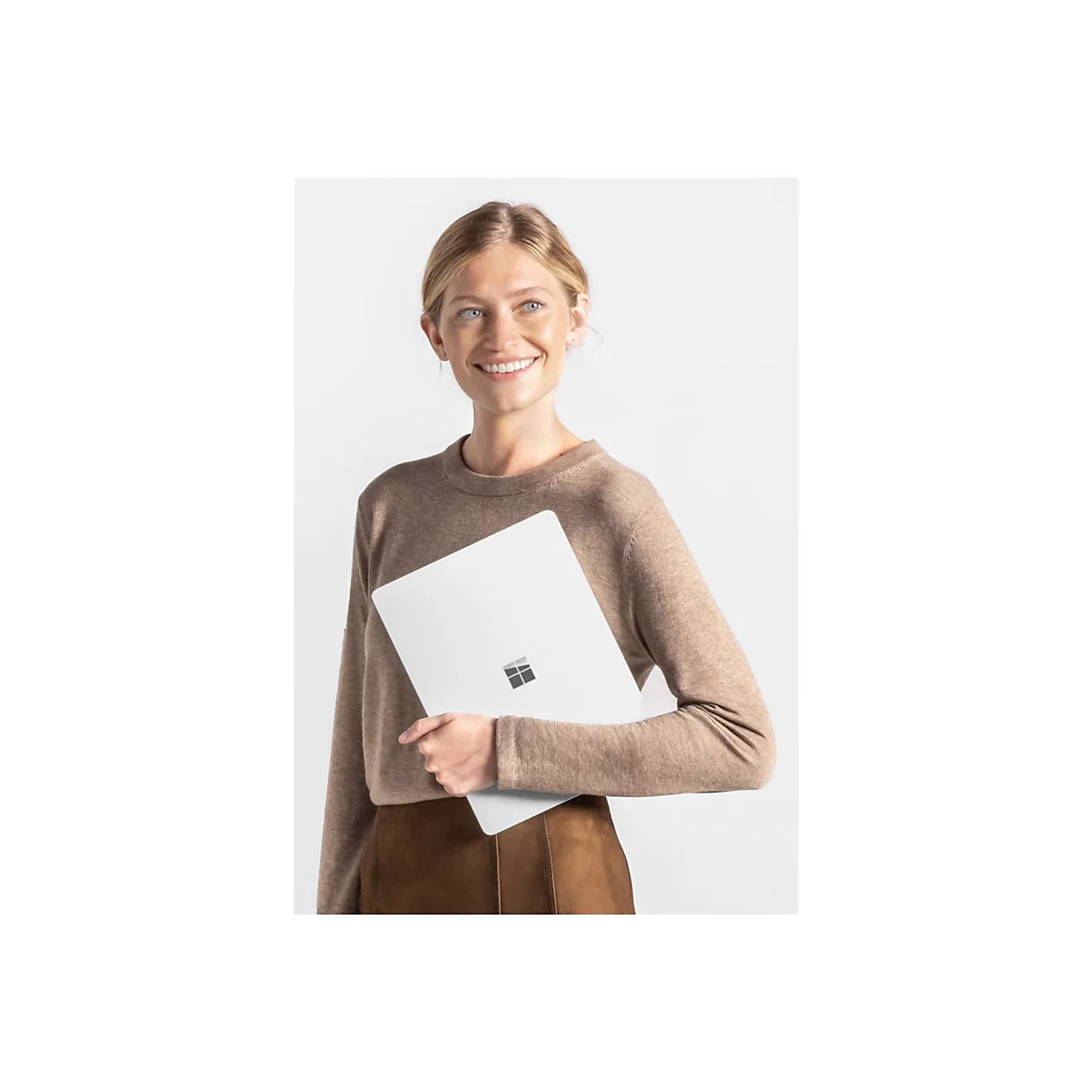 Eine lÃ¤chelnde Frau mit blonden Haaren hÃ¤lt einen weiÃŸen Laptop vor weiÃŸem Hintergrund.