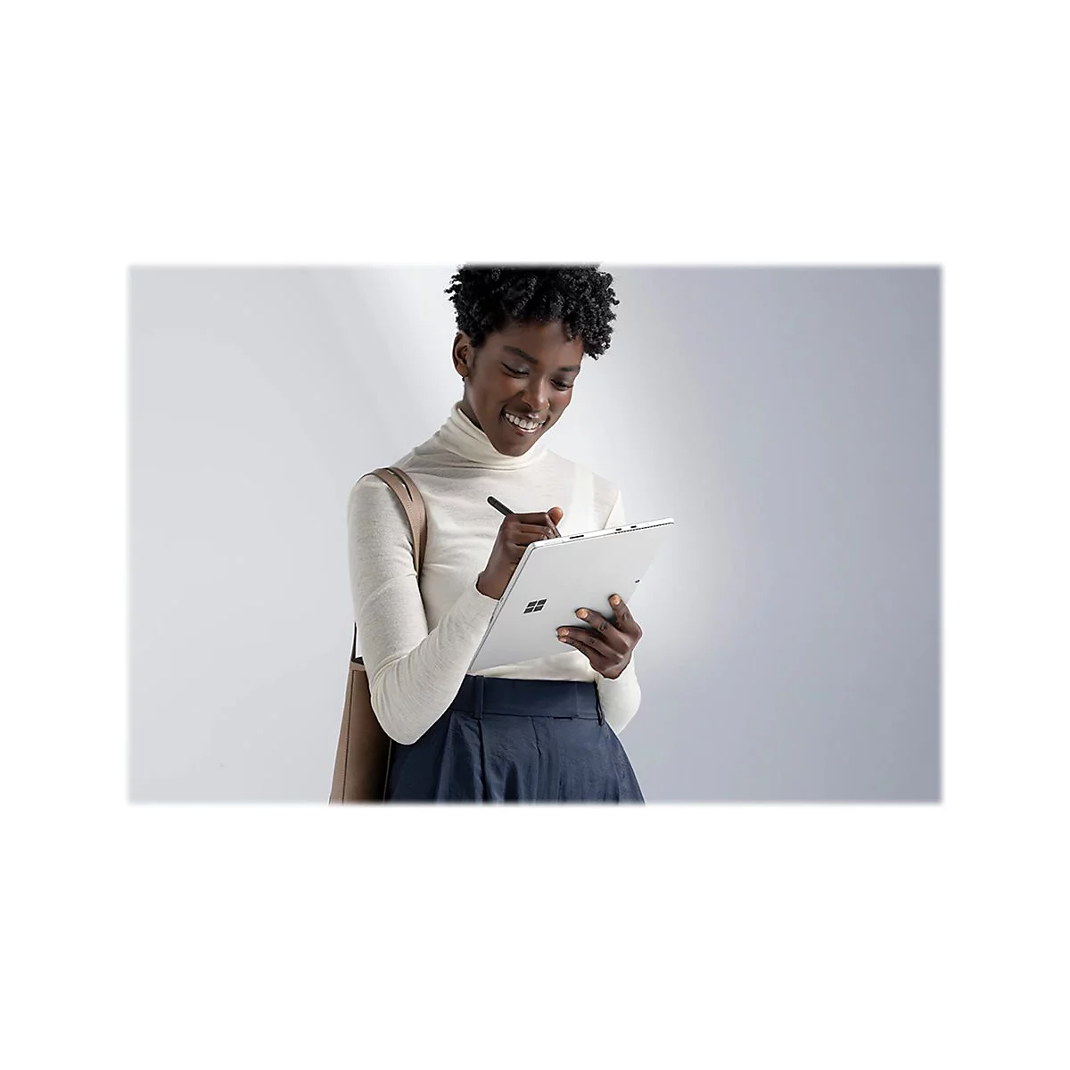 Femme souriante Ã©crivant sur une tablette avec un stylo. Portant un col roulÃ© et une jupe, avec un sac marron.