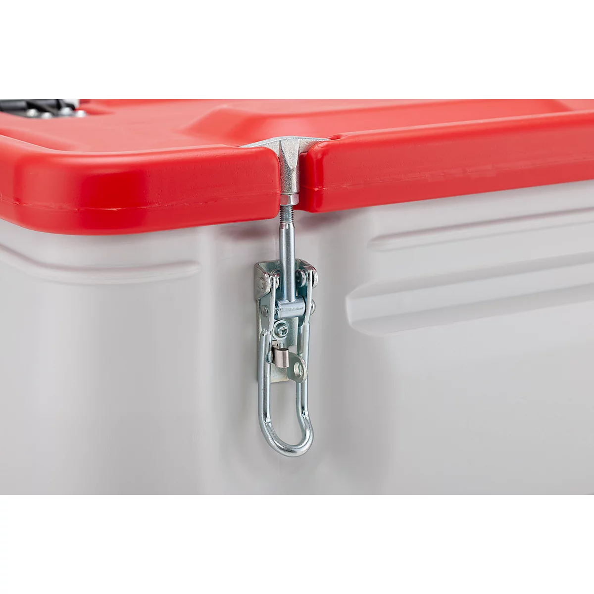 Gros plan sur une partie d'une boîte en plastique. Le couvercle rouge est maintenu par un fermoir en métal fixé à la boîte blanche.