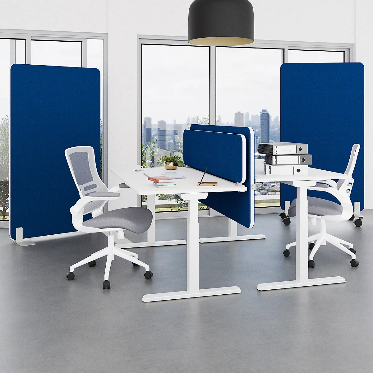Büro mit höhenverstellbaren Tischen, grauen Stühlen und blauen Trennwänden. Im Hintergrund ist eine Stadtansicht zu sehen.