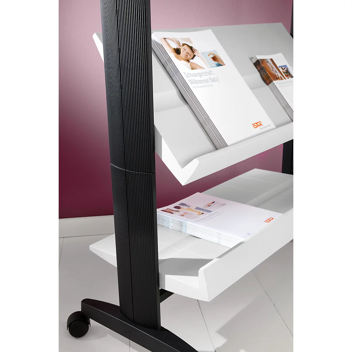 Black shelf with white tray filled with brochures. The stand has wheels, the background is purple.