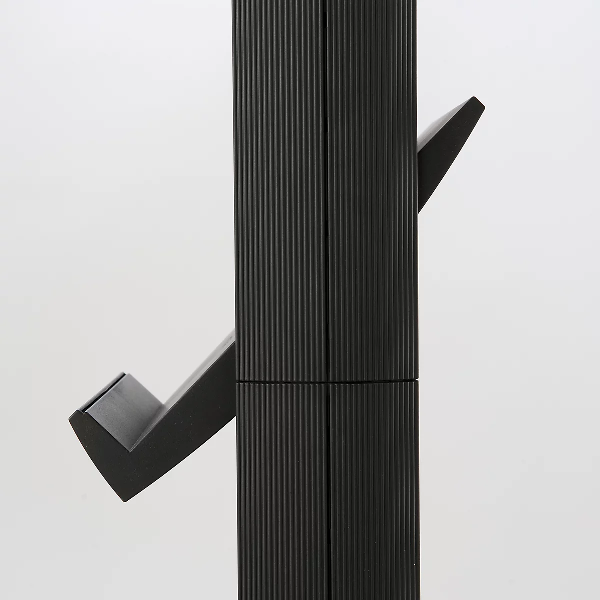 Close-up of a black, ribbed coat rack with protruding hooks.