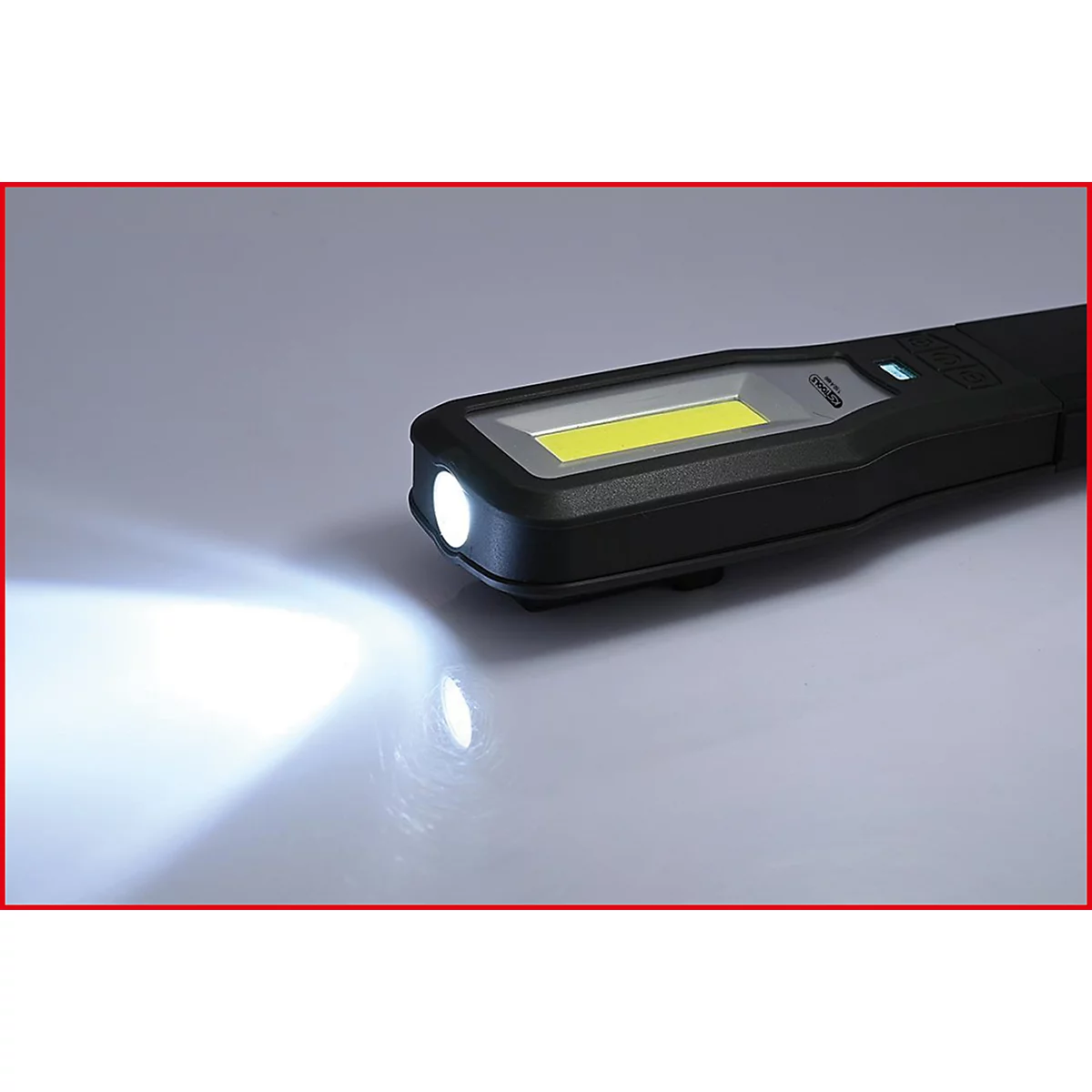 Eine schwarze Stablampe leuchtet auf hellem Untergrund. Das Licht der LED ist gut sichtbar.