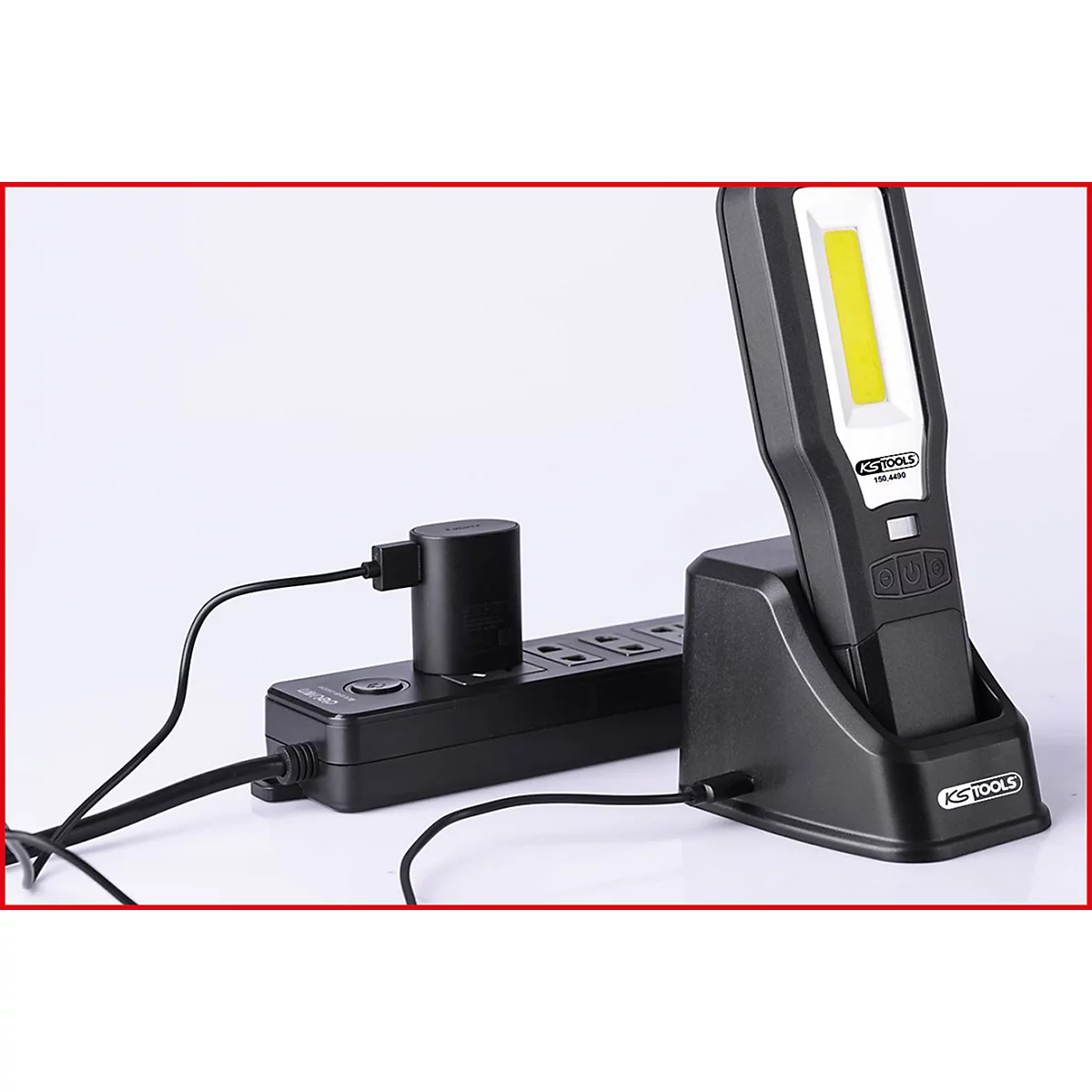 Schwarze LED-Arbeitsleuchte in Ladestation. Steckerleiste mit Stecker verbunden.