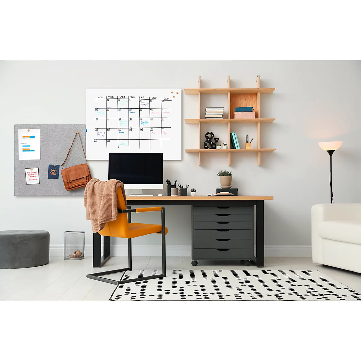 Un espace de travail cosy avec un bureau, un calendrier, un tableau d'affichage et une chaise. Un ordinateur est posé sur le bureau.
