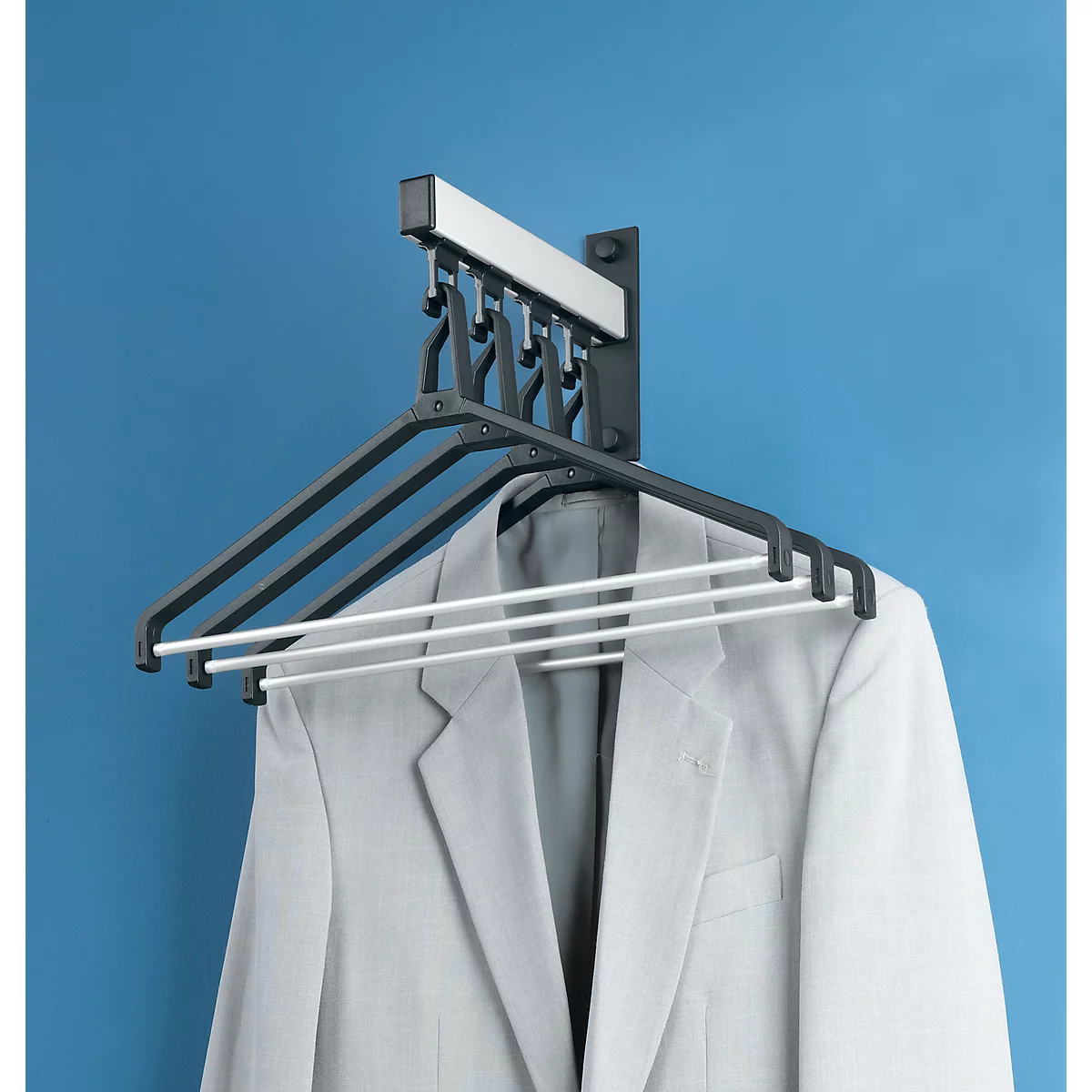 Secadora con chaqueta en pared azul. La secadora tiene varias perchas.