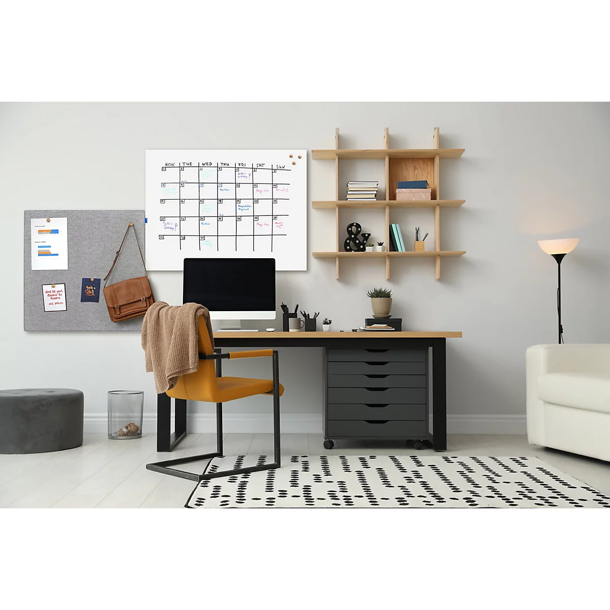 Un espacio de trabajo acogedor con escritorio, calendario, tablón de anuncios y silla. Hay un ordenador y una planta en el escritorio.