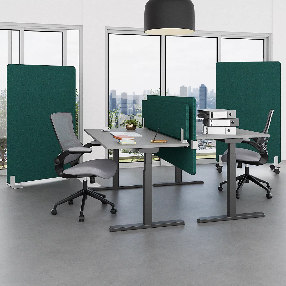 An office featuring multiple desks, chairs, and green partitions in front of large windows overlooking a cityscape.
