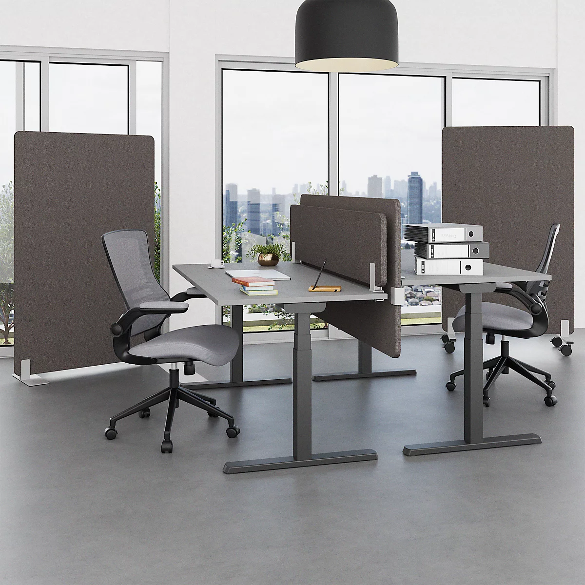 Office with grey desks, dividers and office chairs in front of window front. In the background a city.
