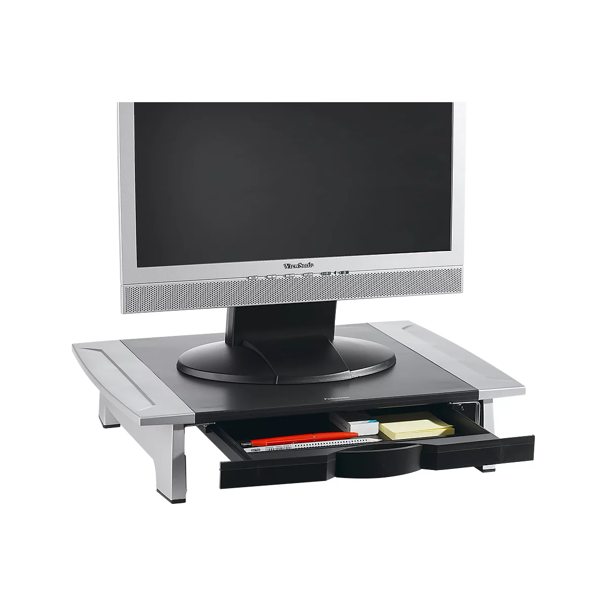 Monitor on a black stand with a drawer. Inside, a red pen, sticky notes, and other small items.