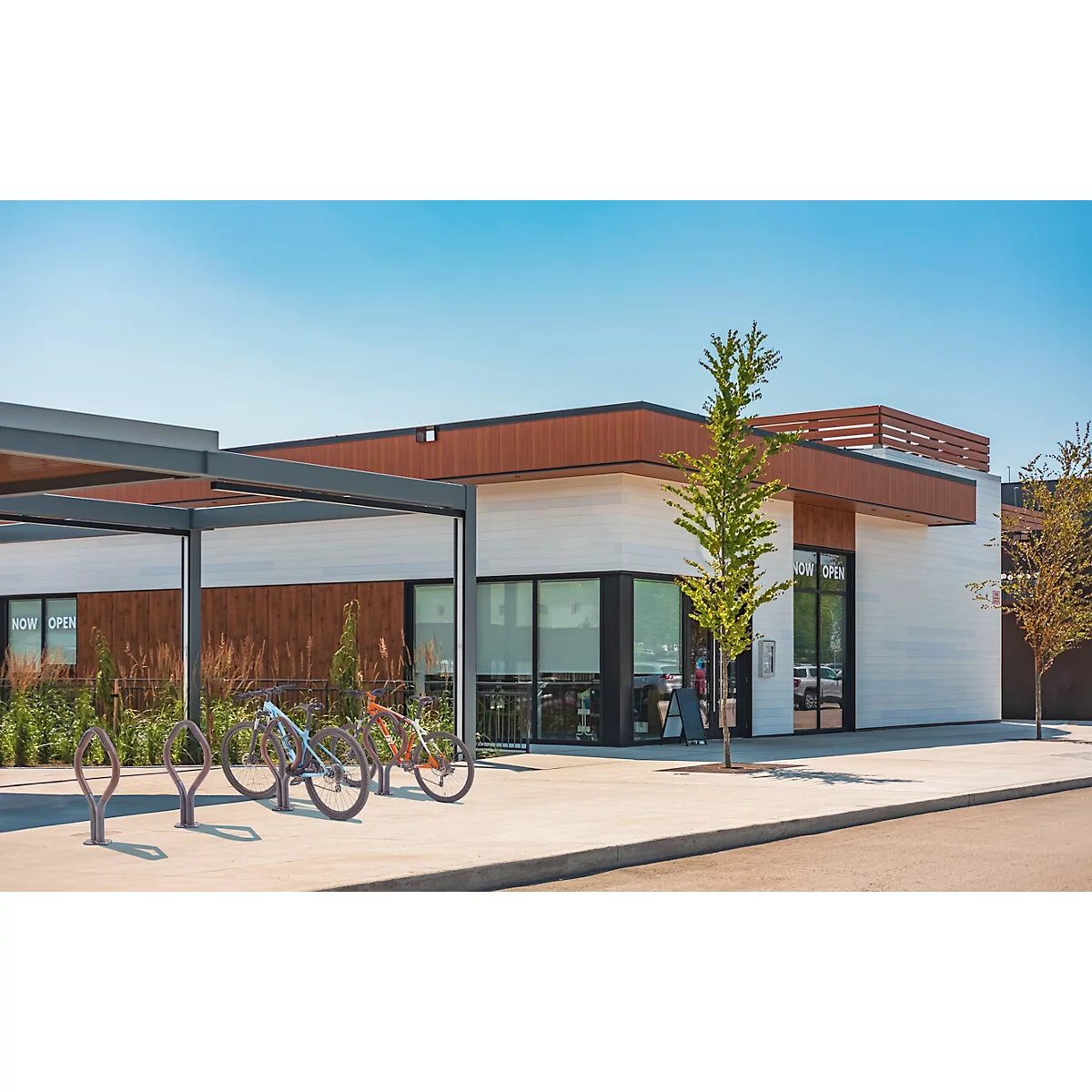 Modern gebouw met bruin hout en witte muren, fietsen ervoor en een open deur.