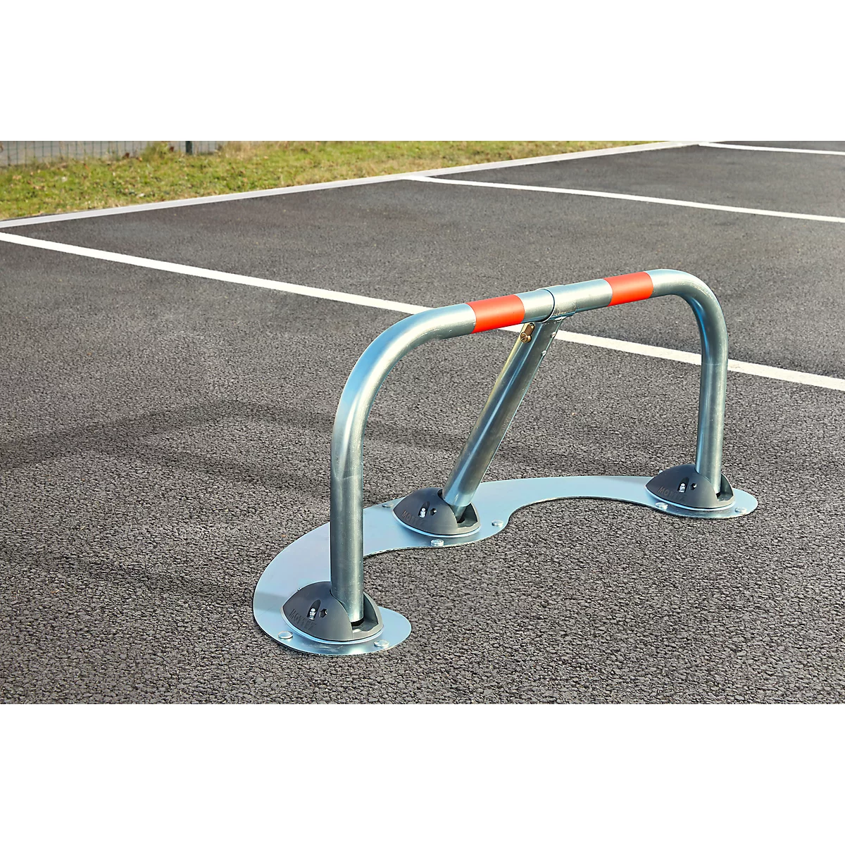 Parking barrier on asphalt, marked in red. It serves as a parking space lock.