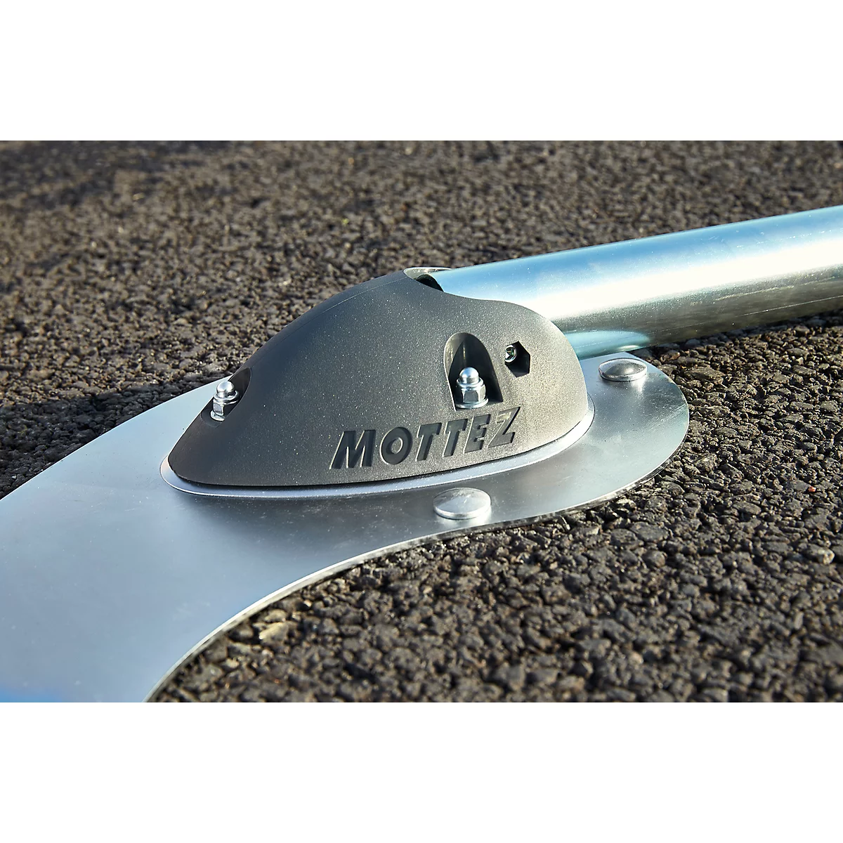 Gray metal construction with the inscription "MOTTEZ" on a black background. A silver pipe is held.