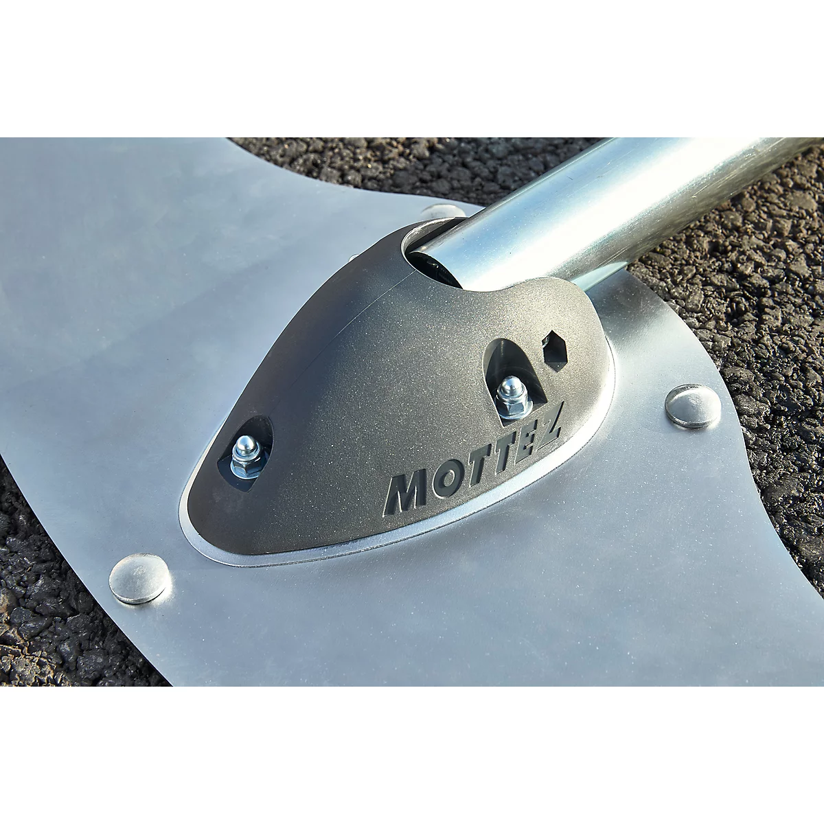 Close-up of a metal device. A black element with the inscription "MOTTEZ" is fixed with screws on a silver plate.