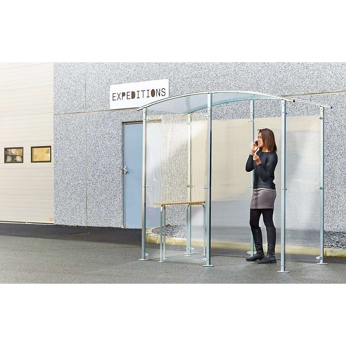 Een vrouw telefoneert in een transparante telefooncel. Op de achtergrond een gebouw met de tekst "EXPEDITIONS".