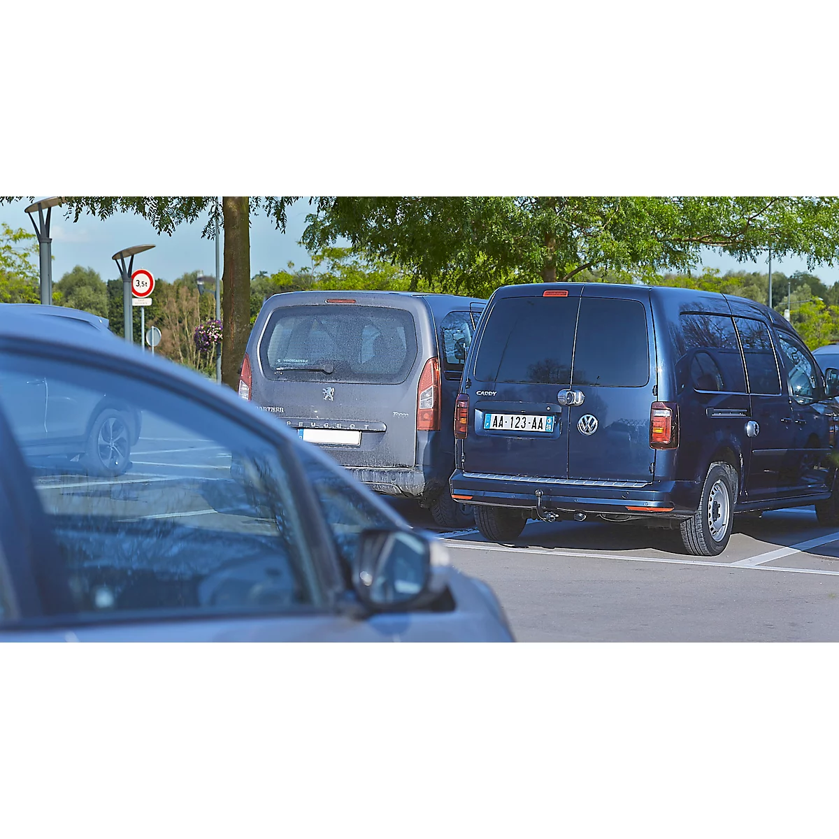 Donkerblauwe auto geparkeerd op een parkeerplaats, omringd door andere auto's.
