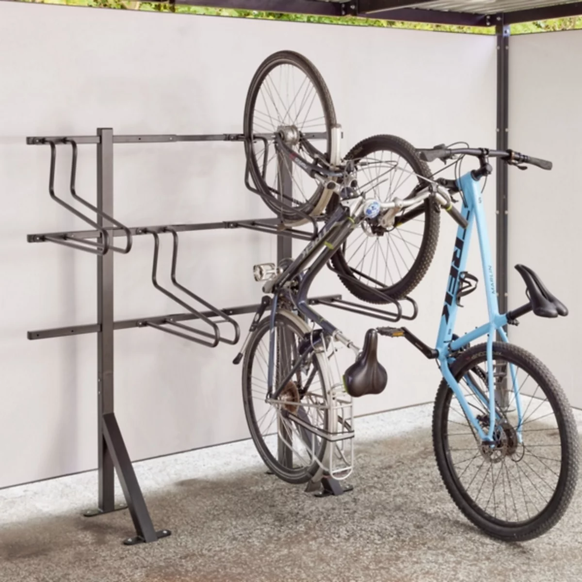 Ein schwarzer Fahrradständer montiert an einer hellen Wand mit einem eingehängten blauen Fahrrad.
