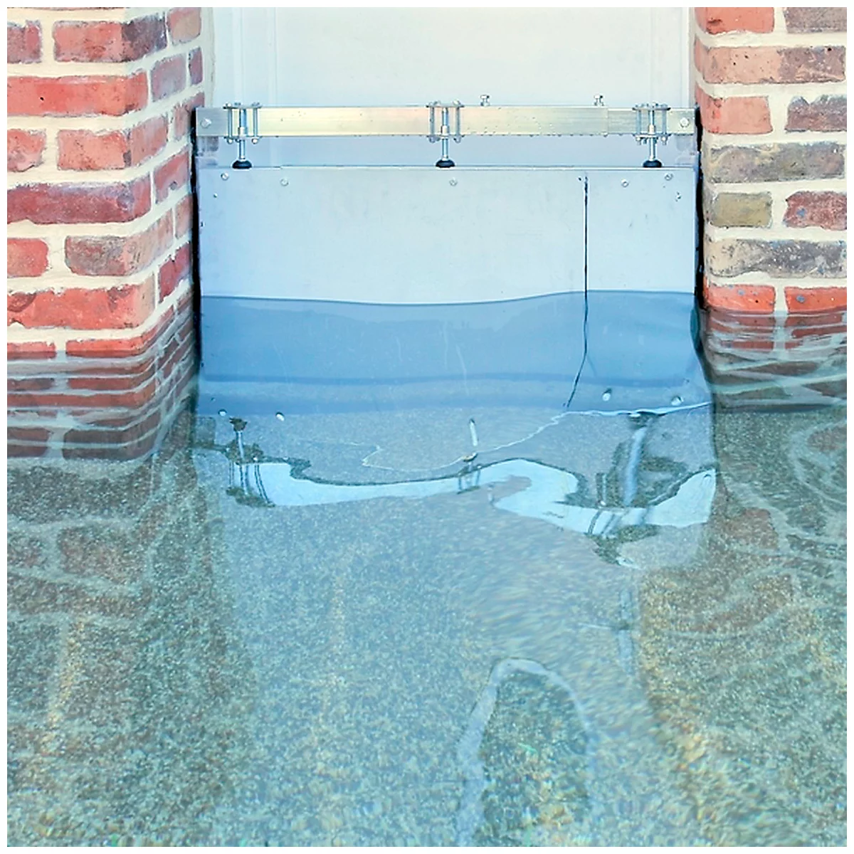 Overstromingsbescherming voor een gebouw gevuld met water. Bakstenen muur links, gladde metalen muur in het midden.