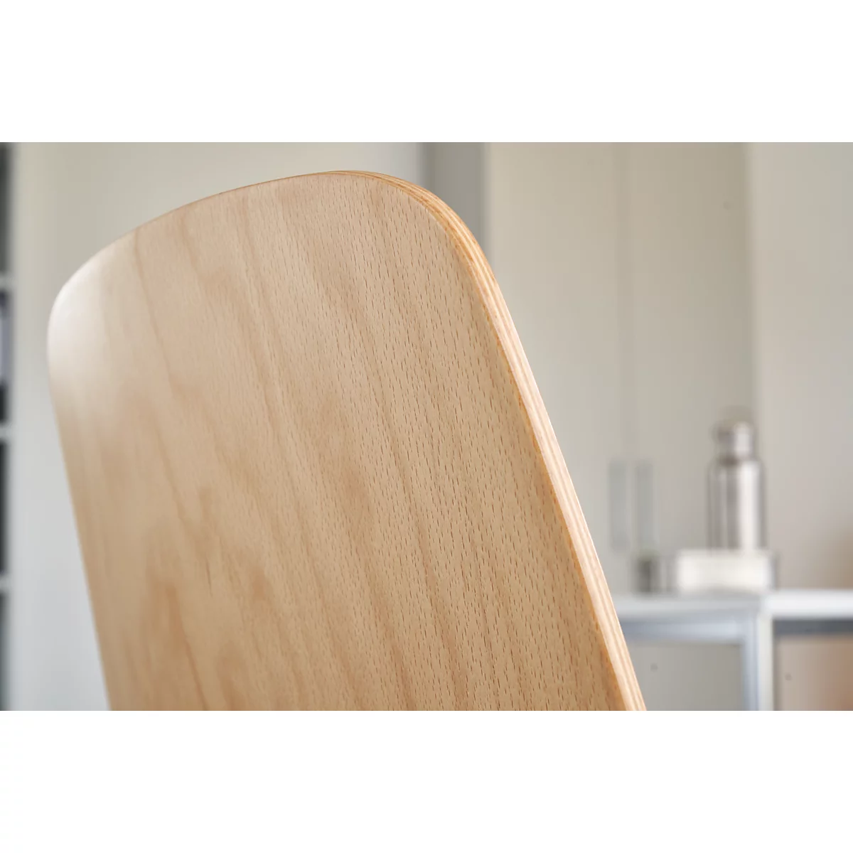 Close-up of the back of a light wooden chair. The wood grain is clearly visible.