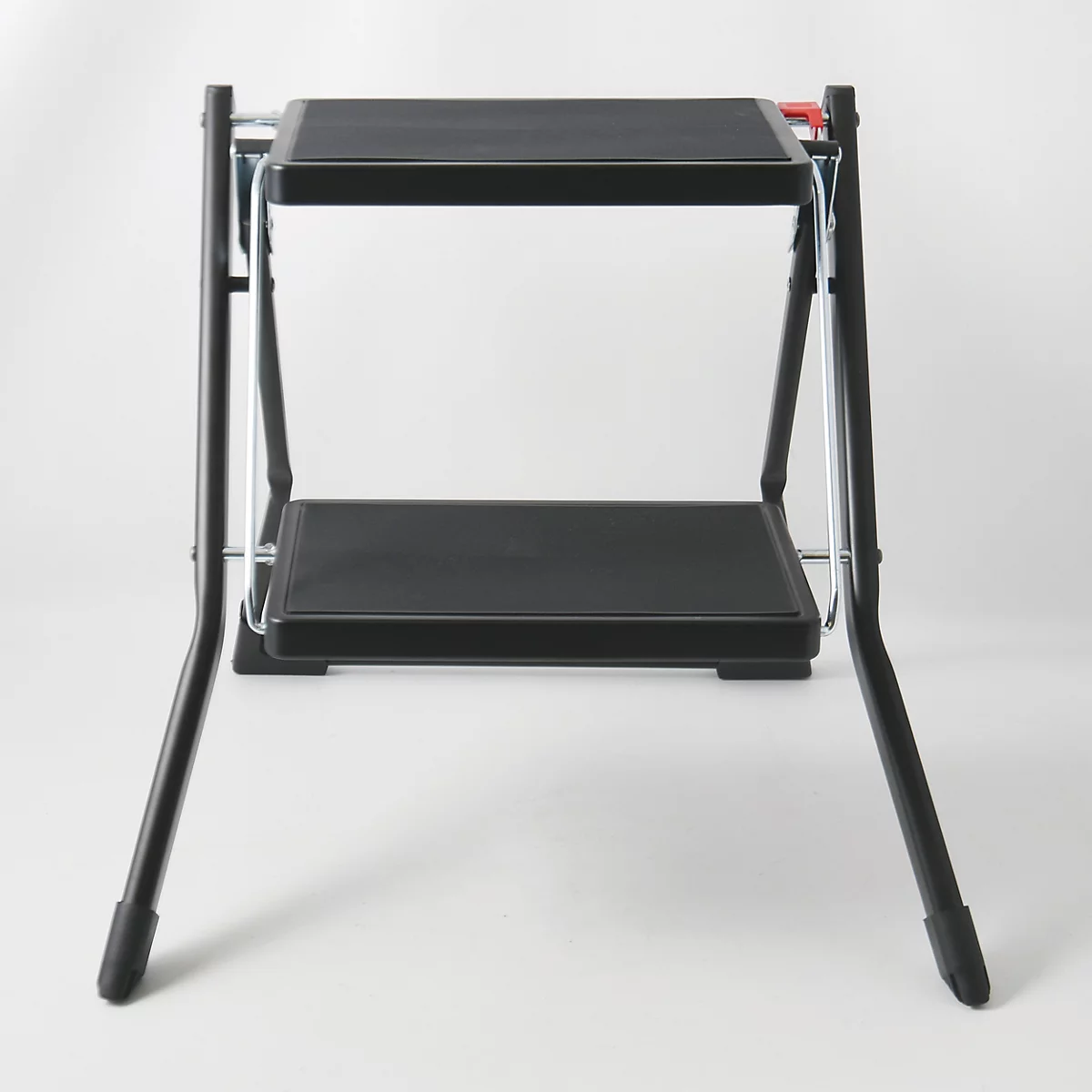 Un tabouret noir à deux marches sur fond blanc.
