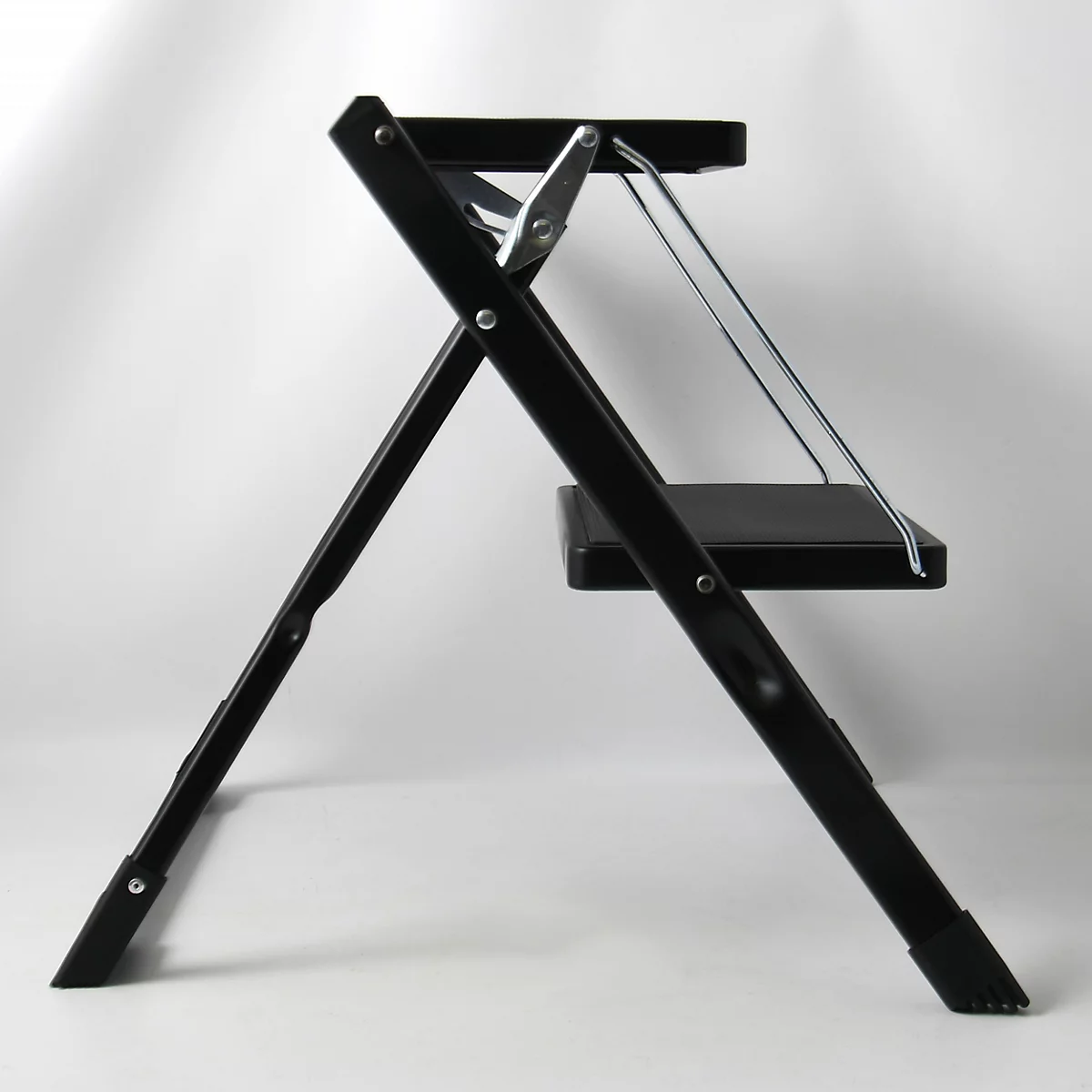 Escabeau noir à deux marches, supports métalliques et fond blanc.