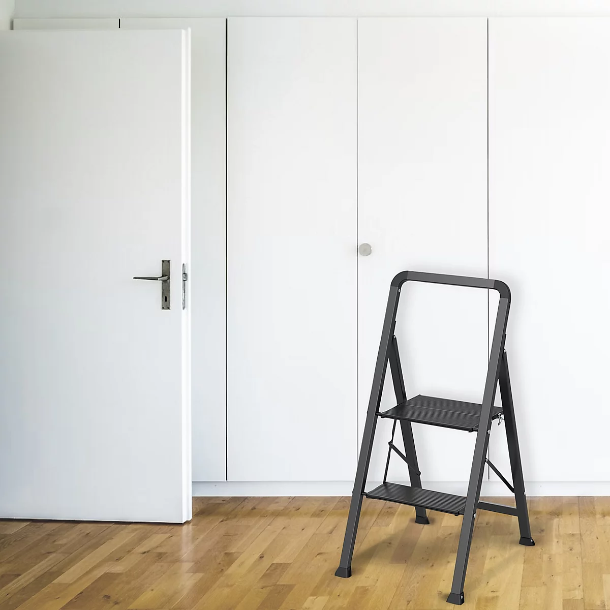 Une échelle noire est posée sur un parquet. On aperçoit une porte blanche et des placards blancs en arrière-plan.
