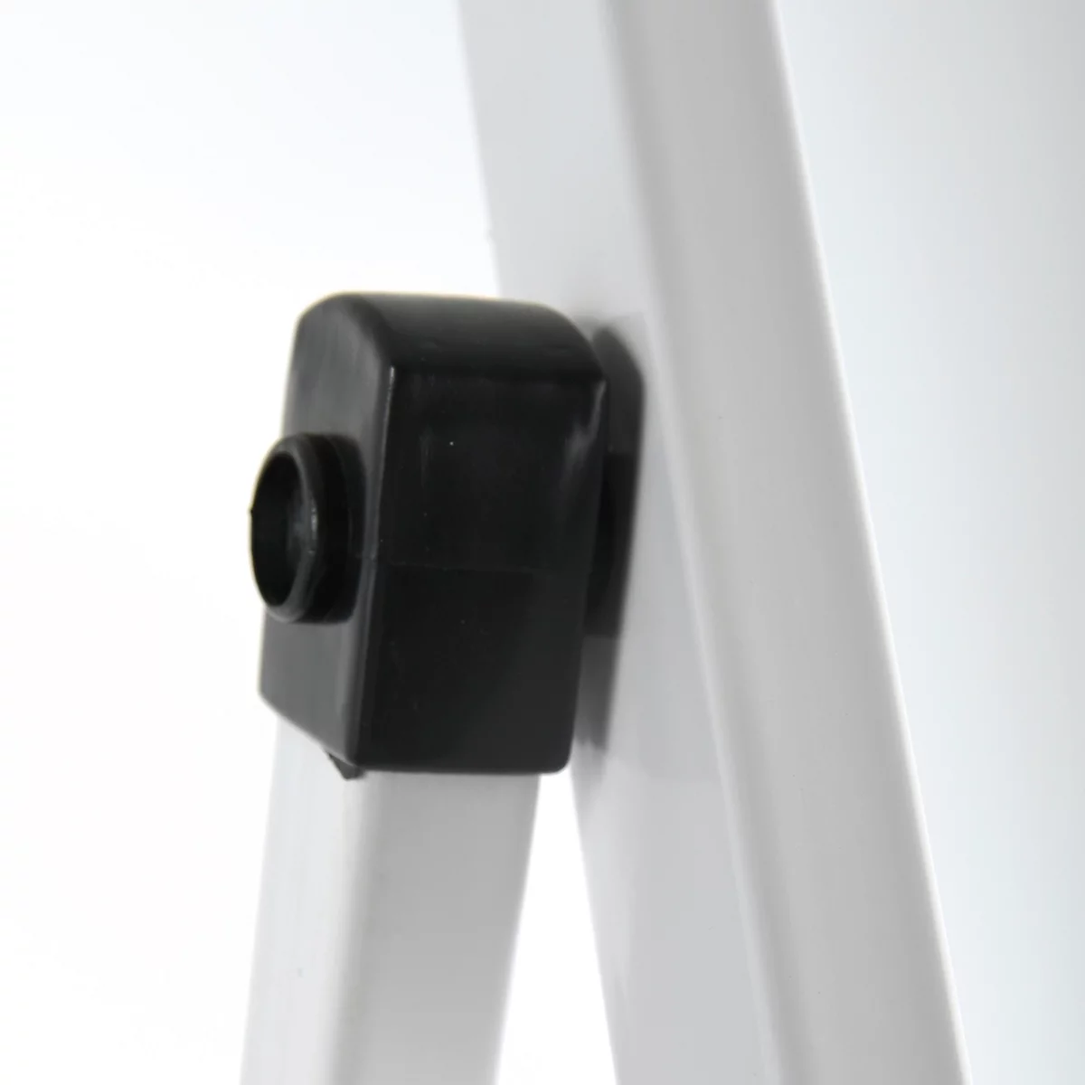 Gros plan d'une pièce en plastique noir fixée sur un cadre blanc. Il y a un trou visible sur la pièce.