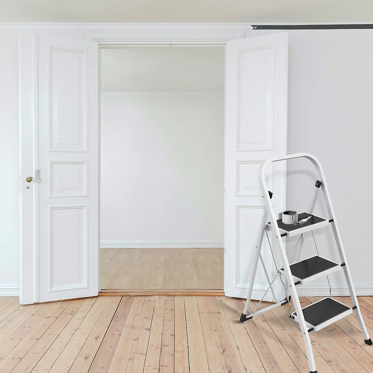 Escalier blanc dans une pièce claire. Portes ouvertes vers la pièce suivante. Tasse à café sur la marche supérieure.