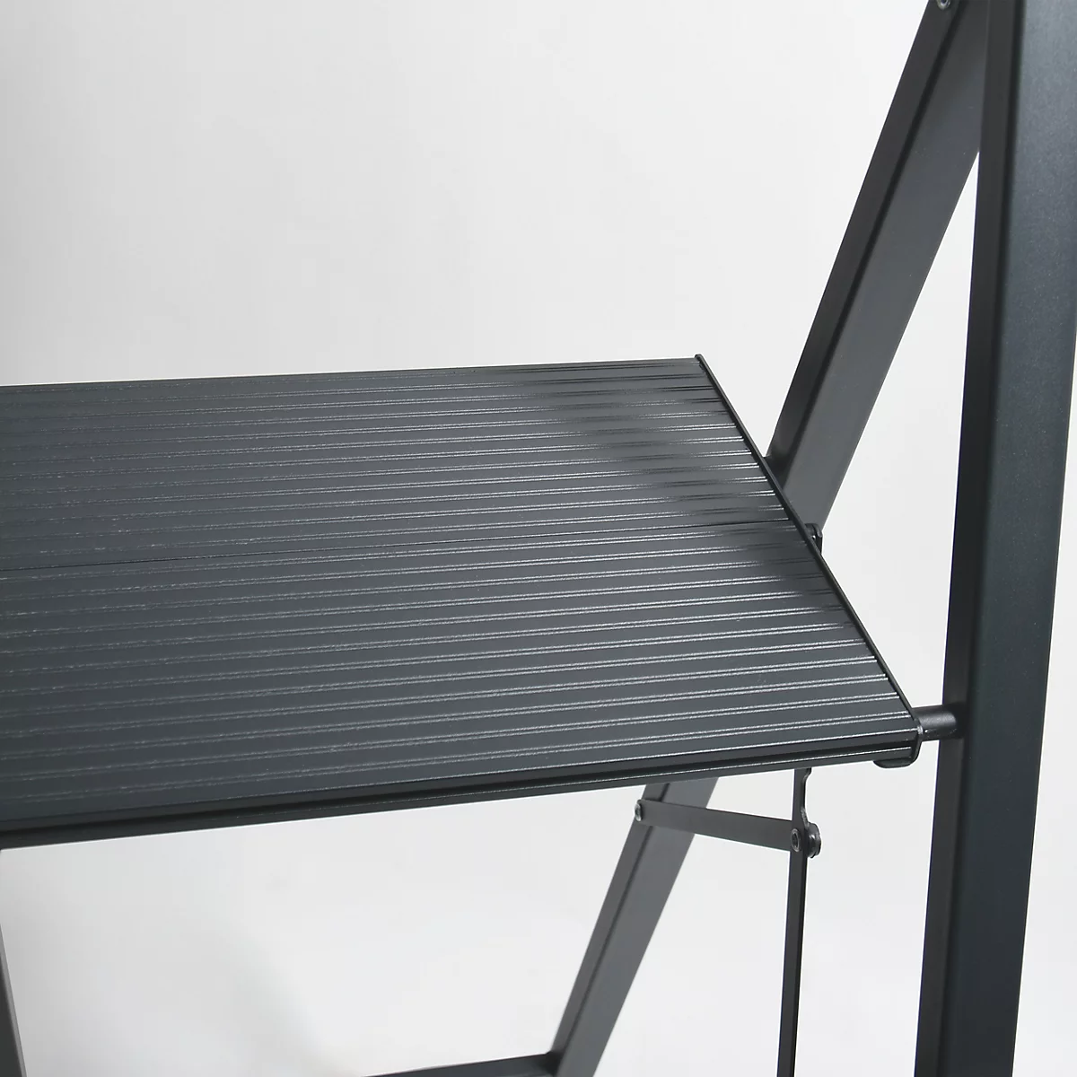 Gros plan d'une plateforme noire et striée d'une structure métallique. Le cadre et les supports sont également noirs.