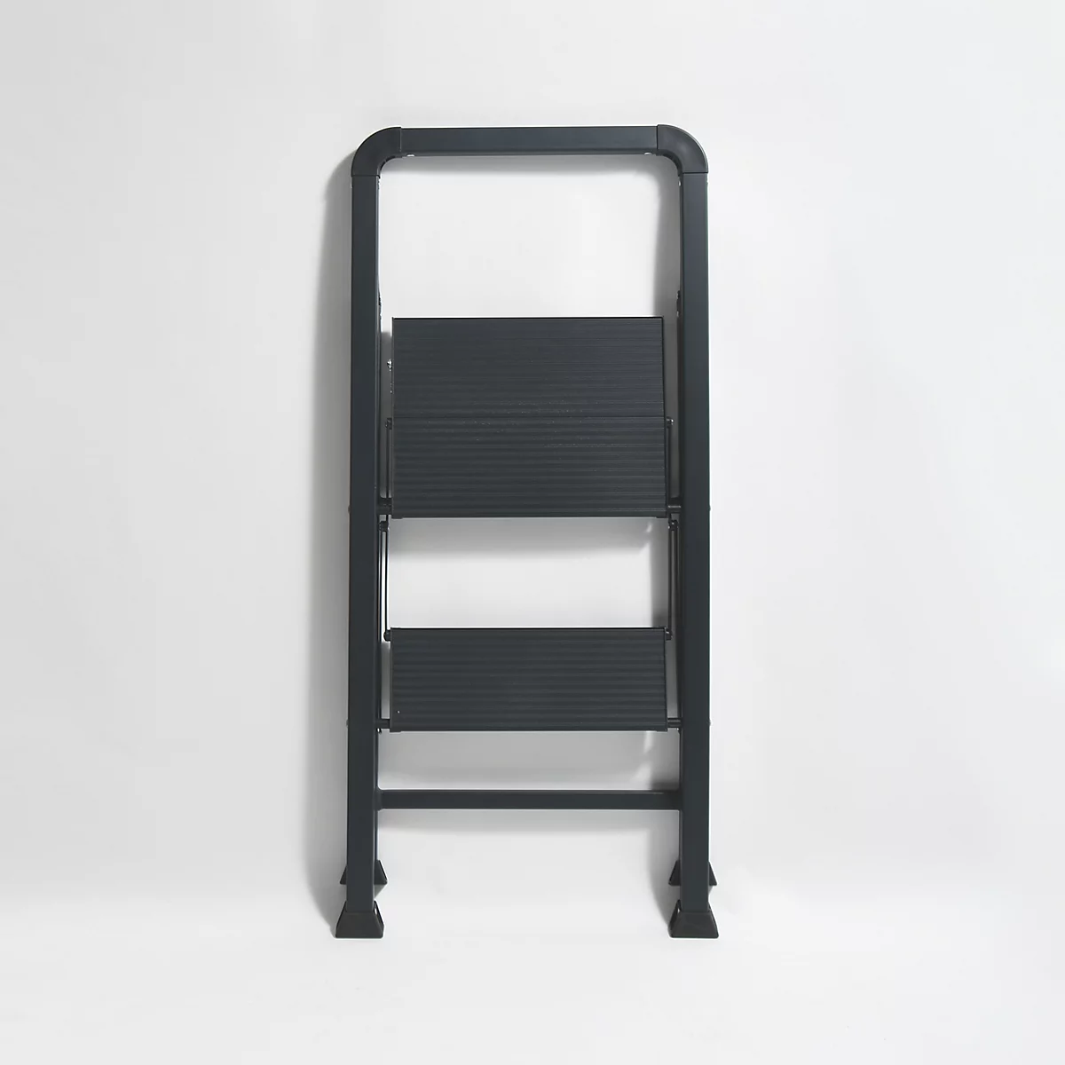 Eine dunkelgraue Trittleiter vor weissem Hintergrund. Drei Stufen und ein Handlauf. Die Leiter ist zusammengeklappt.