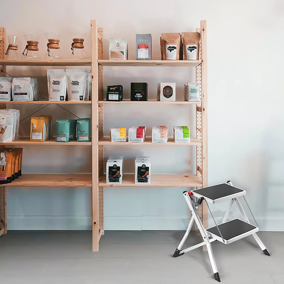 Regale mit Kaffeeprodukten. Ein Trittschemel steht davor.