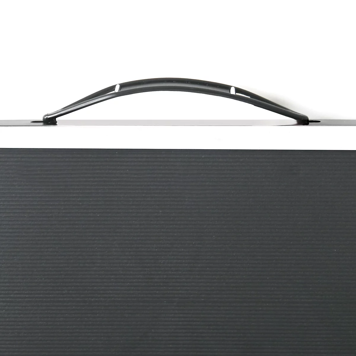 Detailaufnahme eines schwarzen Koffers mit Griff und geriffelter Oberfläche. Der Griff ist leicht gebogen.