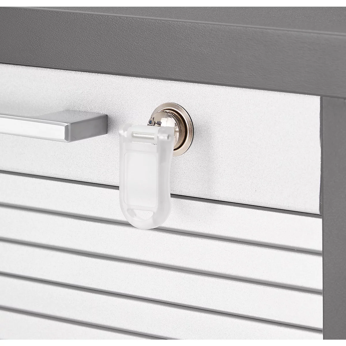 Detailweergave: Een sleutel met een plastic sleutelhanger zit in een slot, naast een eenvoudige zilveren handgreep.