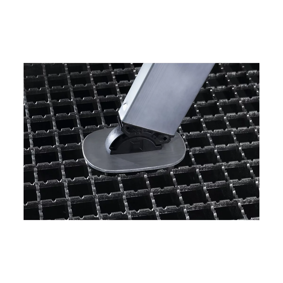 Gros plan d'un pied en métal posé sur une grille en métal. La jambe est argentée, la base du pied est noire.