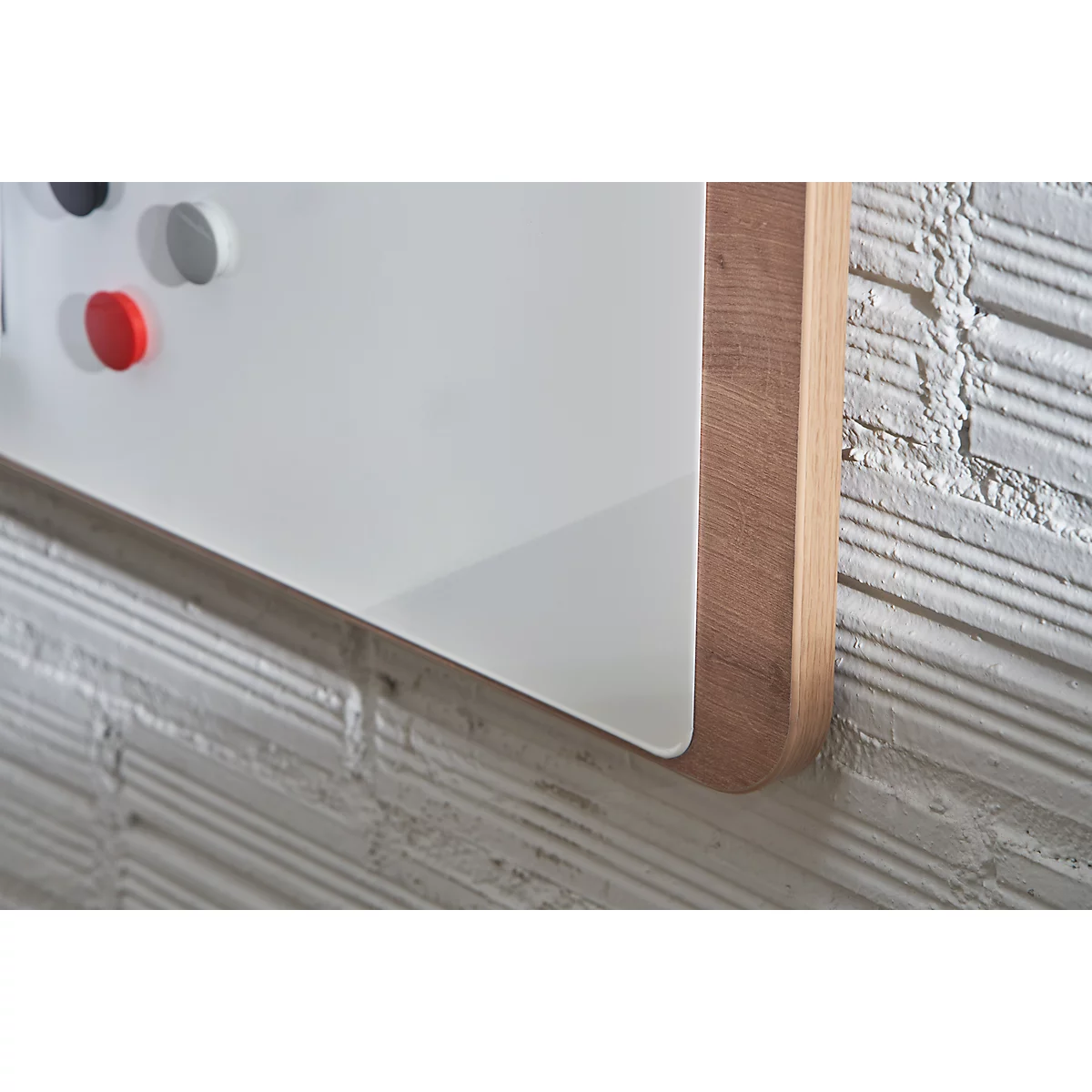 Detail of a white magnetic board with a wooden frame, corner detail, brick wall.